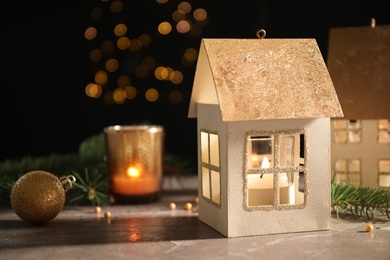Composition with house shaped candle holders on table against dark blurred background. Christmas decoration