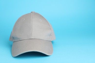 Photo of Stylish grey baseball cap on light blue background. Space for text