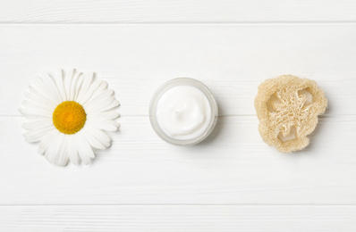 Photo of Jar of cream, loofah and chamomile on white wooden table, flat lay