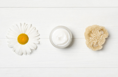 Jar of cream, loofah and chamomile on white wooden table, flat lay