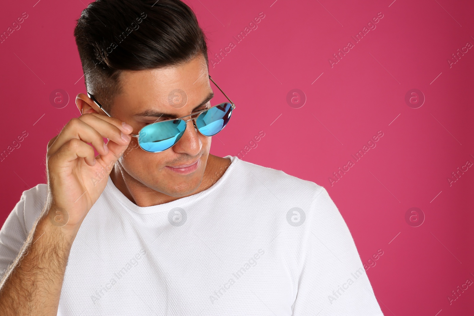 Photo of Handsome man wearing sunglasses on pink background. Space for text