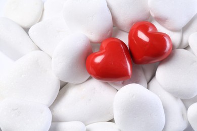 Photo of Decorative hearts on white pebble stones, top view