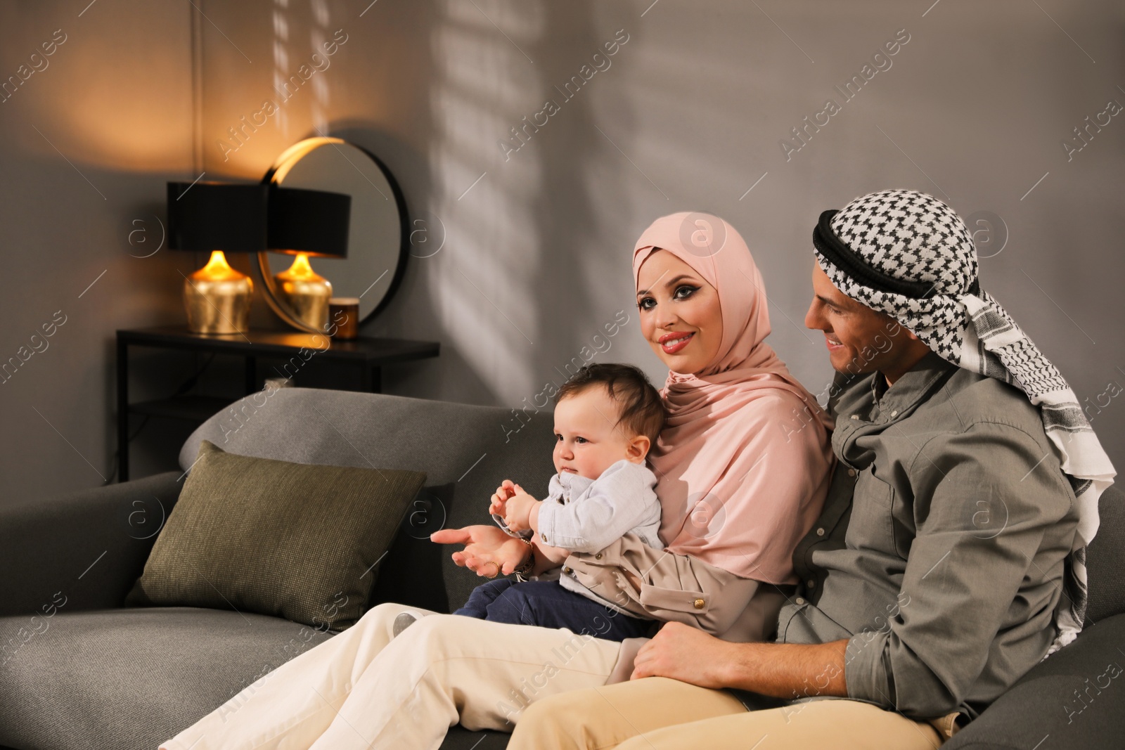 Photo of Happy Muslim family with little son in living room