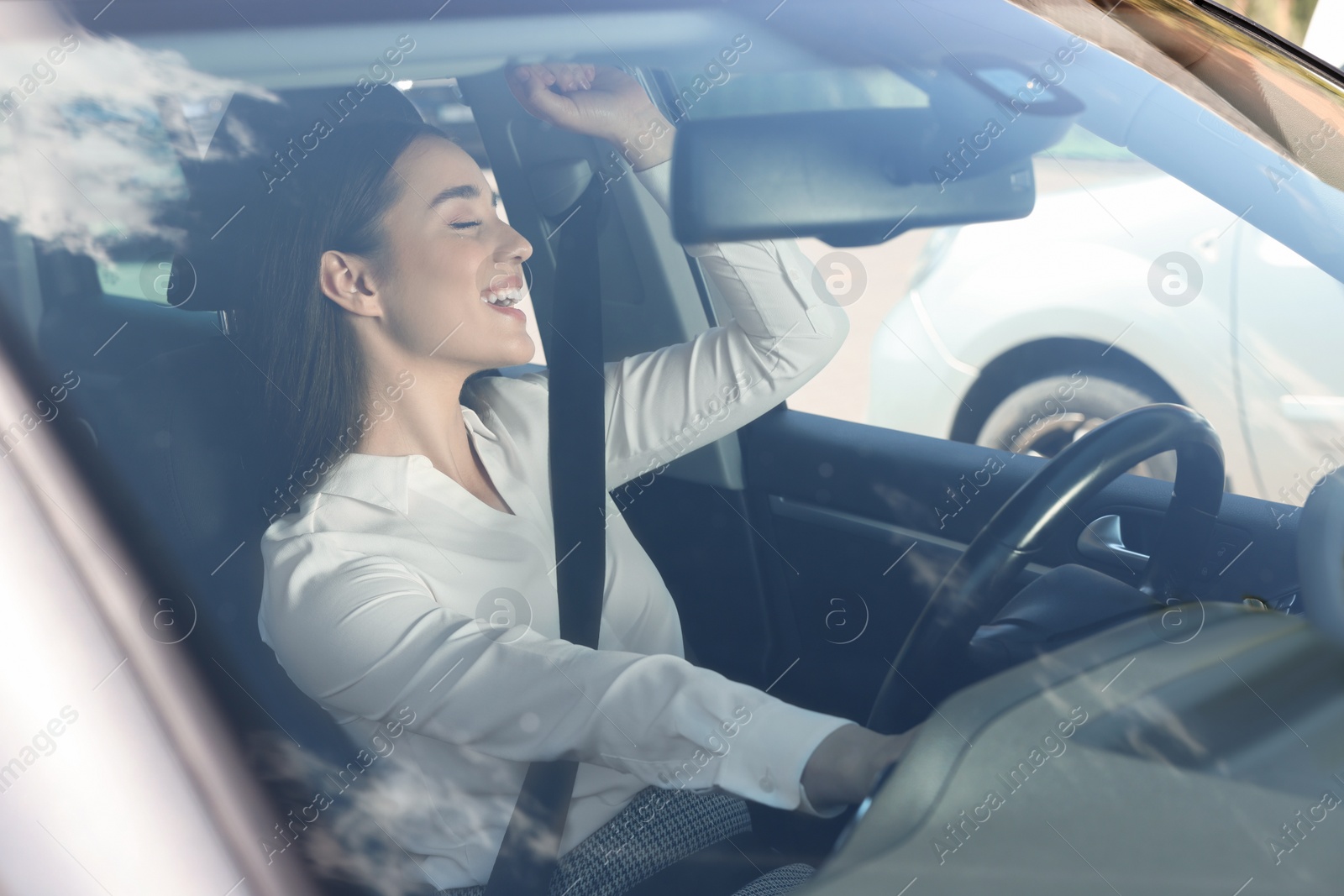 Photo of Listening to radio while driving. Beautiful young woman enjoying music in car, view through windshield