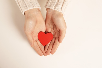 Photo of Woman holding paper heart on white background, top view with space for text