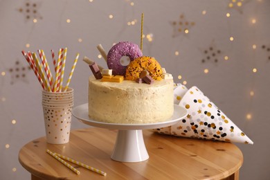 Delicious cake decorated with sweets and festive items on wooden table