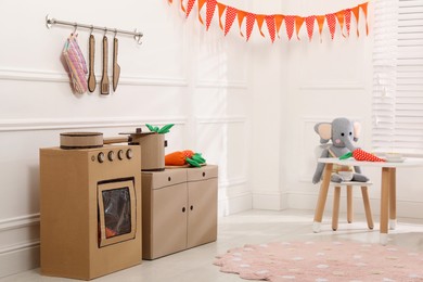 Toy cardboard kitchen with stove and utensils at home
