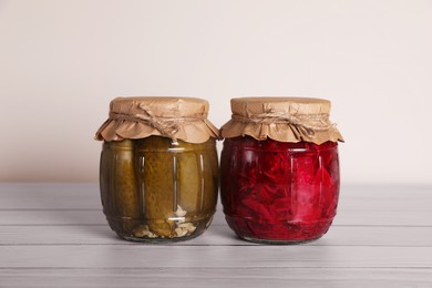 Jars with pickled vegetables on white wooden table