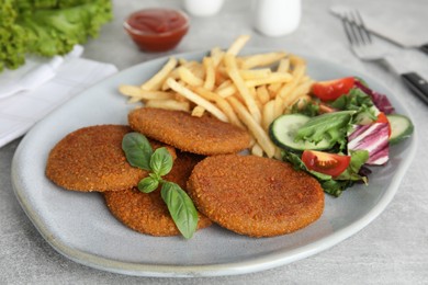 Photo of Delicious fried breaded cutlets with garnish on grey table
