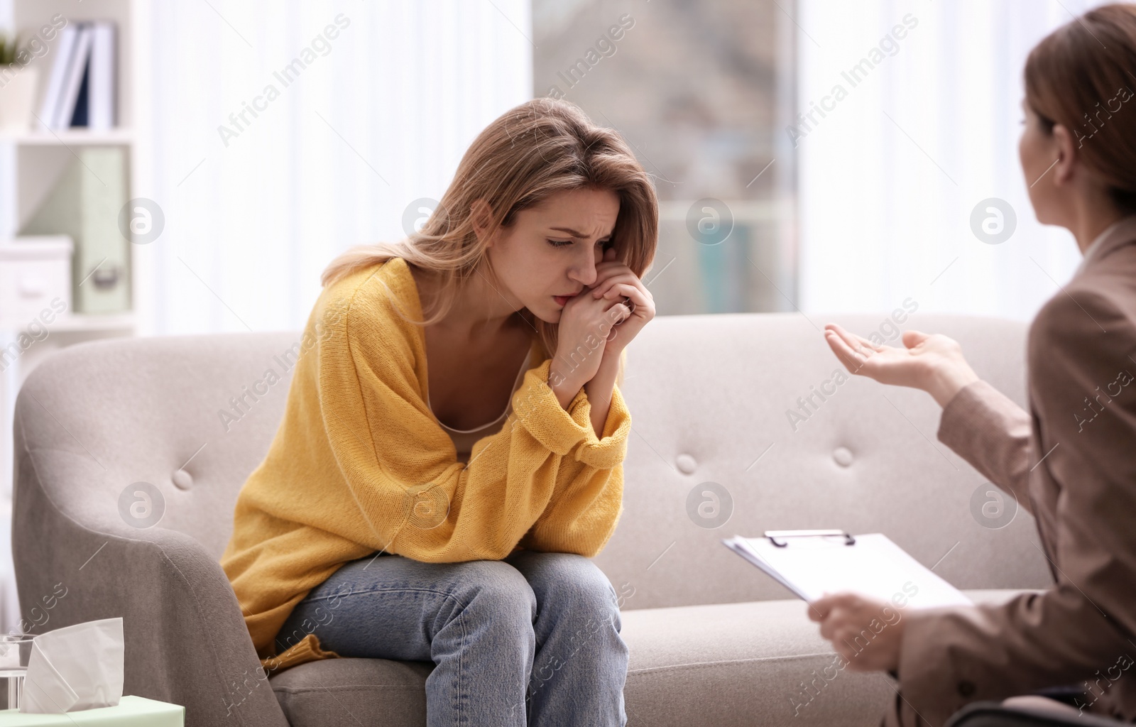 Photo of Psychotherapist working with young woman in light office