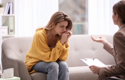 Psychotherapist working with young woman in light office