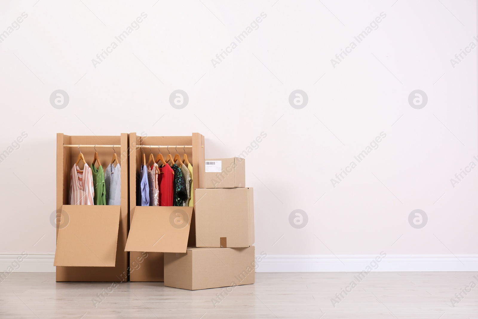 Photo of Wardrobe boxes with clothes against light wall indoors. Space for text