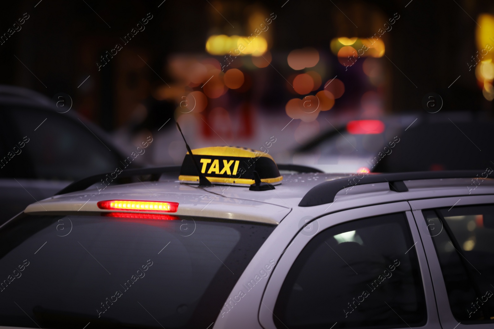 Photo of Taxi car with yellow checkered sign on city street in evening, closeup