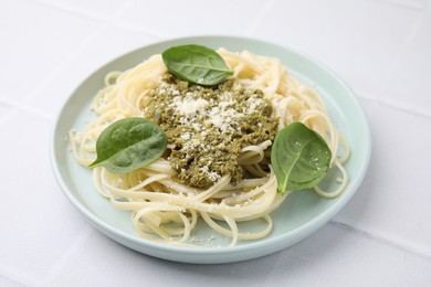 Photo of Tasty pasta with spinach, cheese and sauce on white tiled table