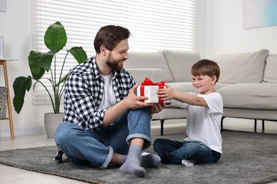 Photo of Happy Father's day. Son giving gift box to his dad at home