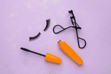 Image of False eyelashes, curler and mascara on violet background, flat lay