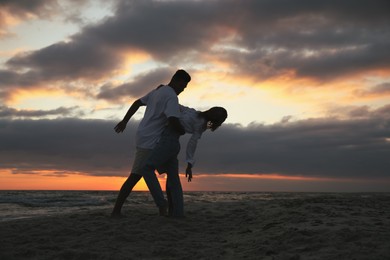 Photo of Happy couple dancing on beach at sunset