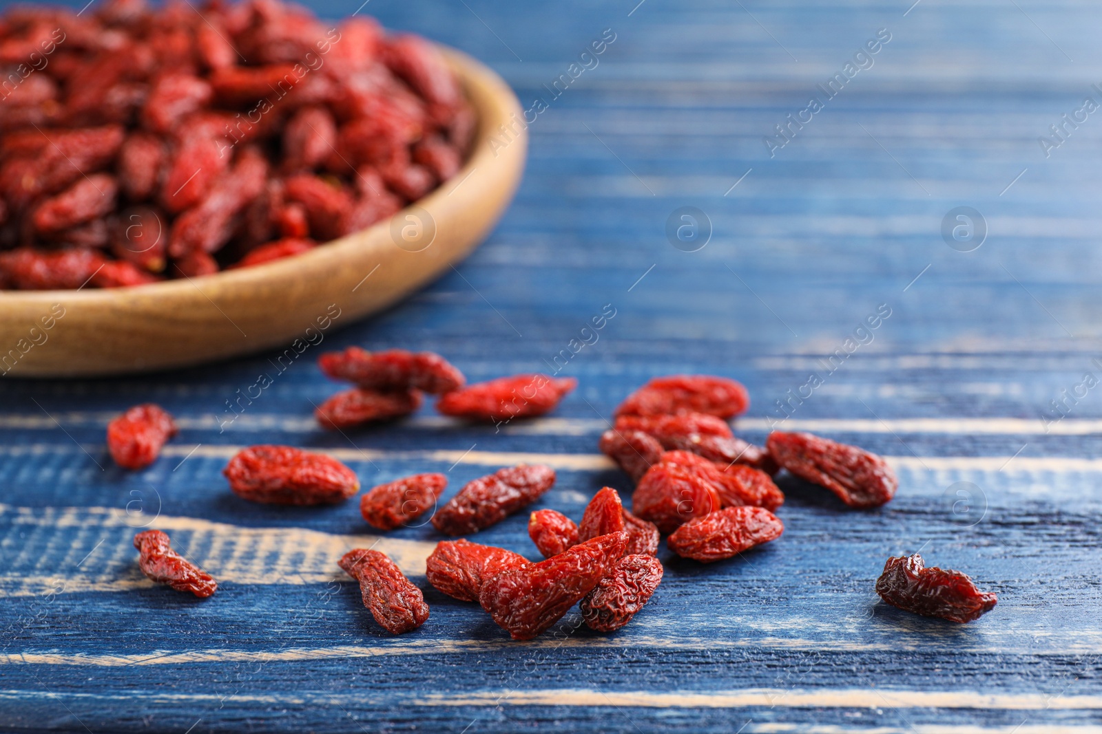 Photo of Dry goji berries on blue wooden table, closeup