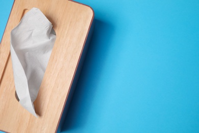 Holder with paper tissues on light blue background, top view. Space for text