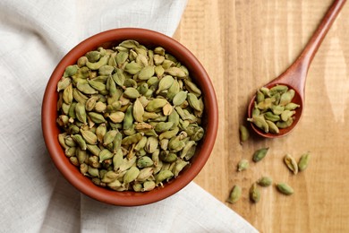 Photo of Dry cardamom pods on wooden table, flat lay