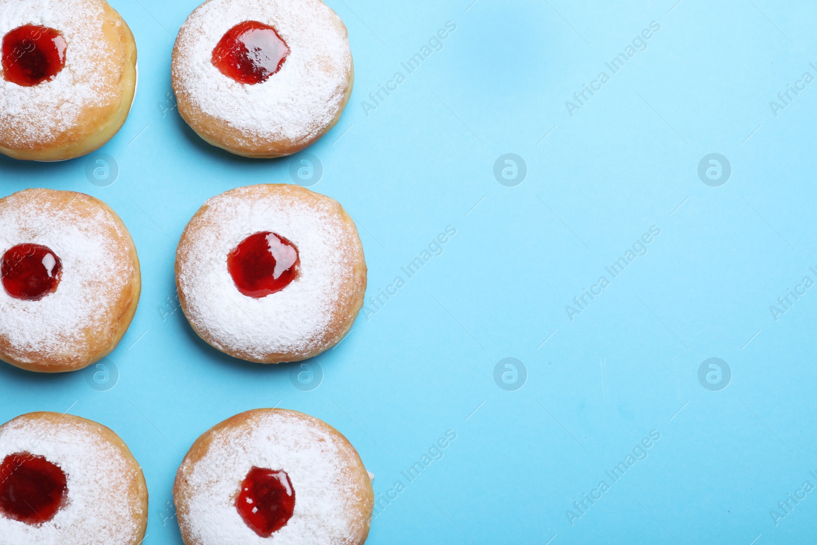 Photo of Hanukkah doughnuts with jelly and sugar powder 
on blue background, flat lay. Space for text