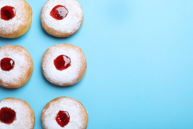 Photo of Hanukkah doughnuts with jelly and sugar powder 
on blue background, flat lay. Space for text