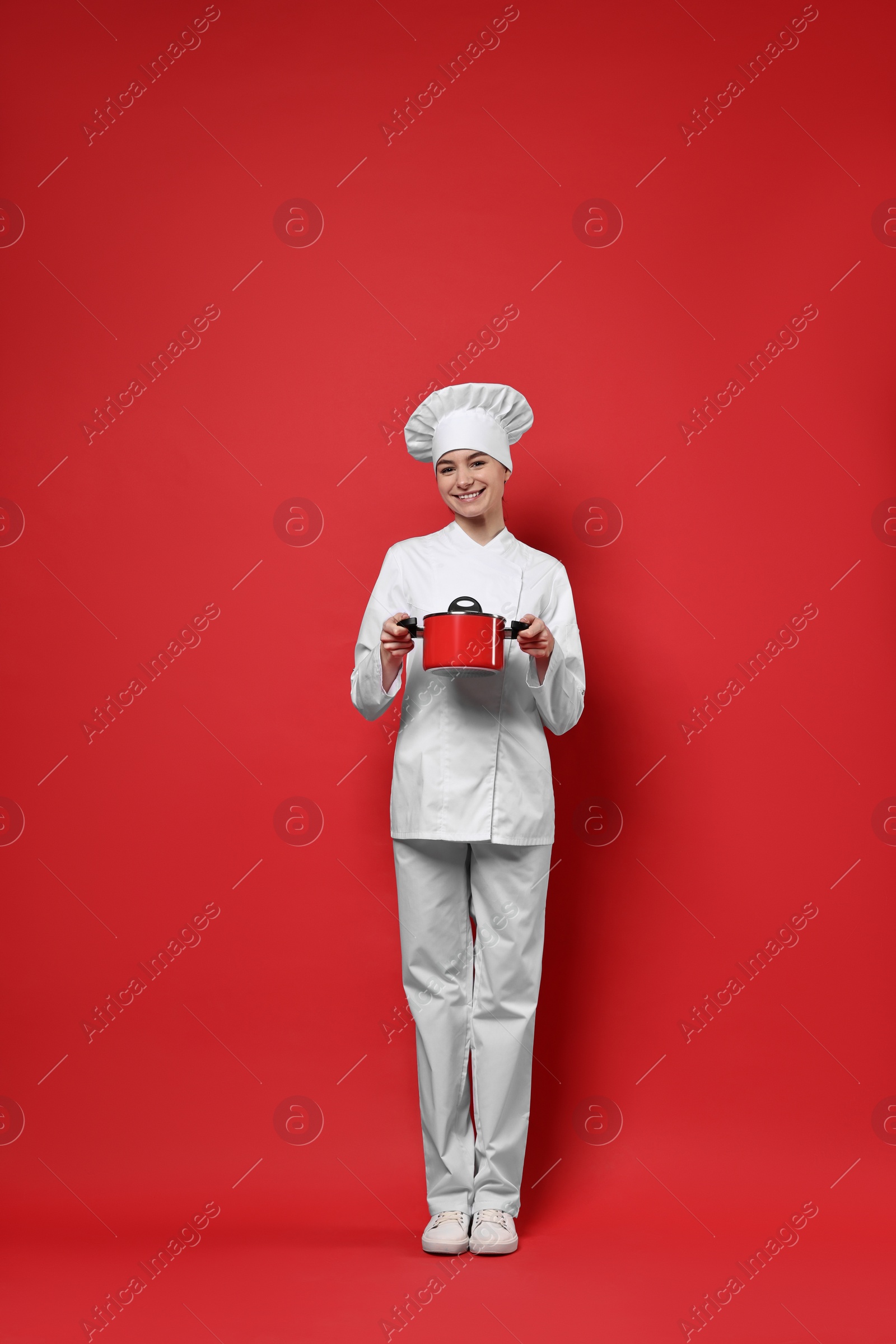 Photo of Professional chef with cooking pot on red background