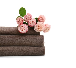 Stack of clean folded towels with flowers on white background