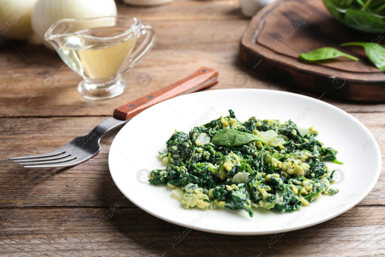 Photo of Tasty cooked spinach served on wooden table. Healthy food