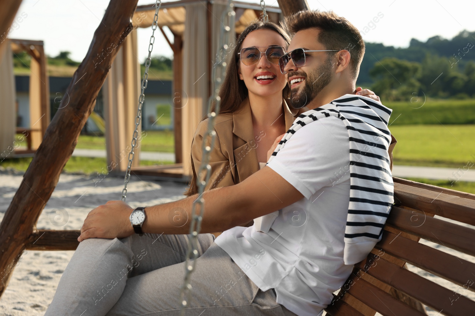 Photo of Romantic date. Beautiful couple spending time together on swing bench outdoors