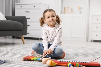 Little girl playing toy xylophone at home