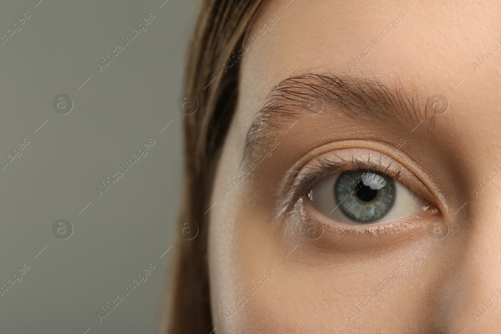Photo of Woman with beautiful natural eyelashes on grey background, closeup
