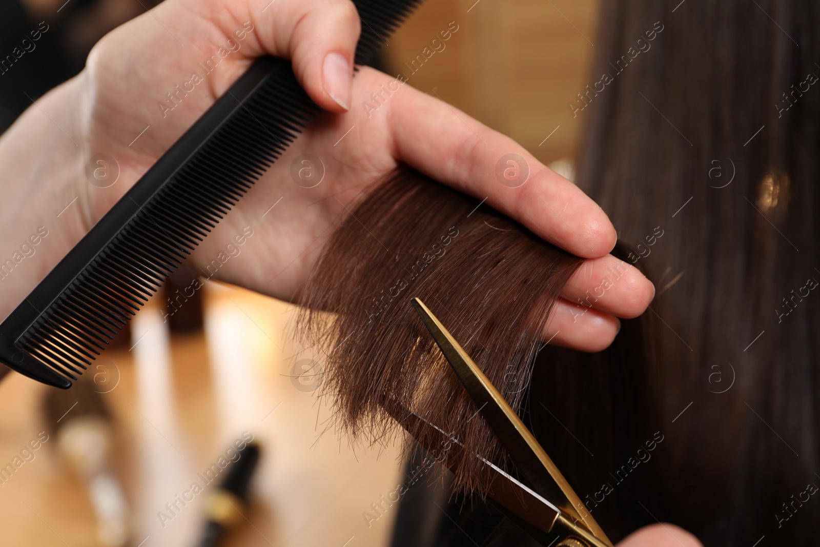 Photo of Hairdresser cutting client's hair with scissors in salon, closeup