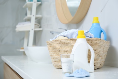 Bottles of detergent and children's clothes on countertop in bathroom