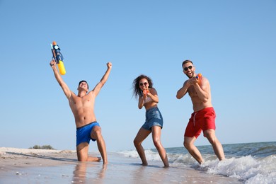 Friends with water guns having fun on beach