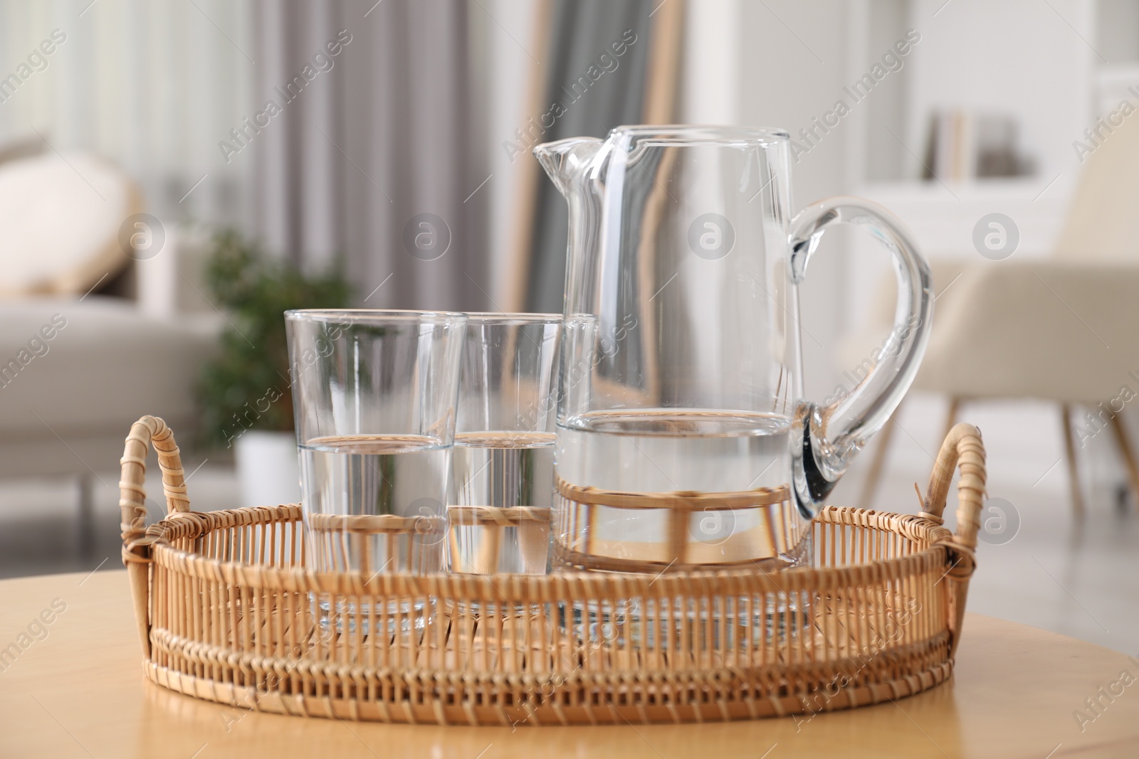 Photo of Jug and glasses with clear water on table indoors, closeup