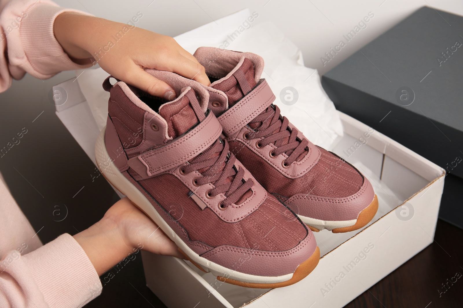 Photo of Girl taking out new sneakers from box against light grey background, closeup