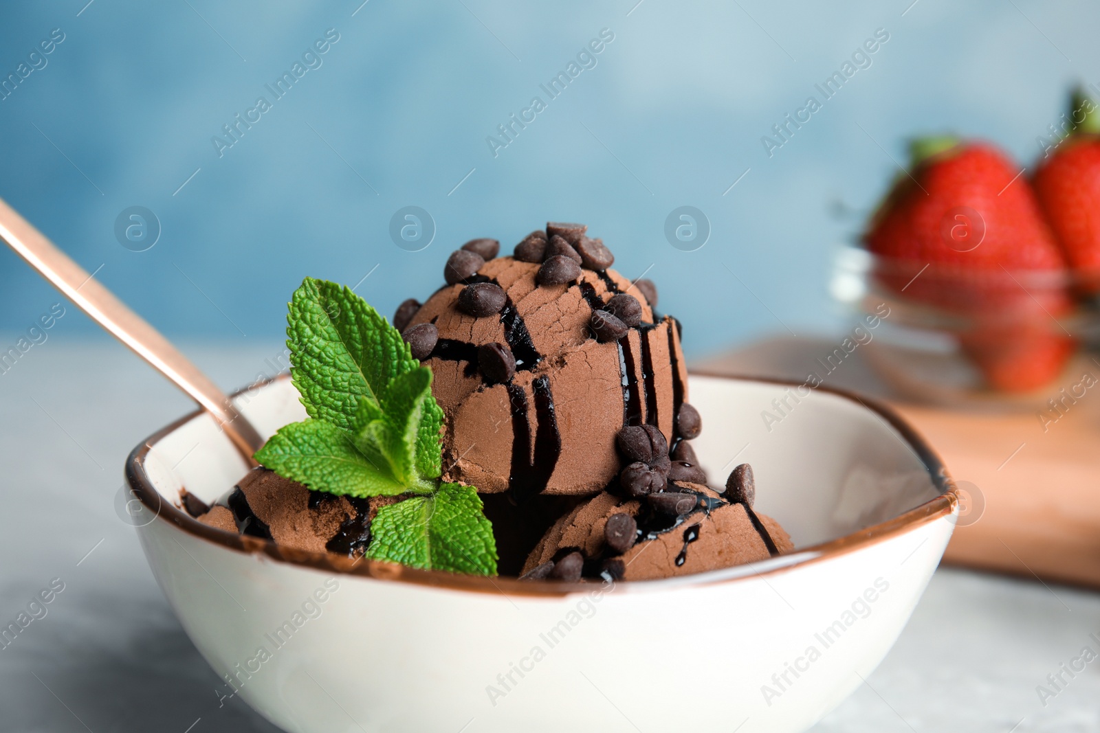 Photo of Bowl of chocolate ice cream with mint on table, closeup. Space for text
