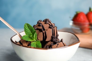 Photo of Bowl of chocolate ice cream with mint on table, closeup. Space for text