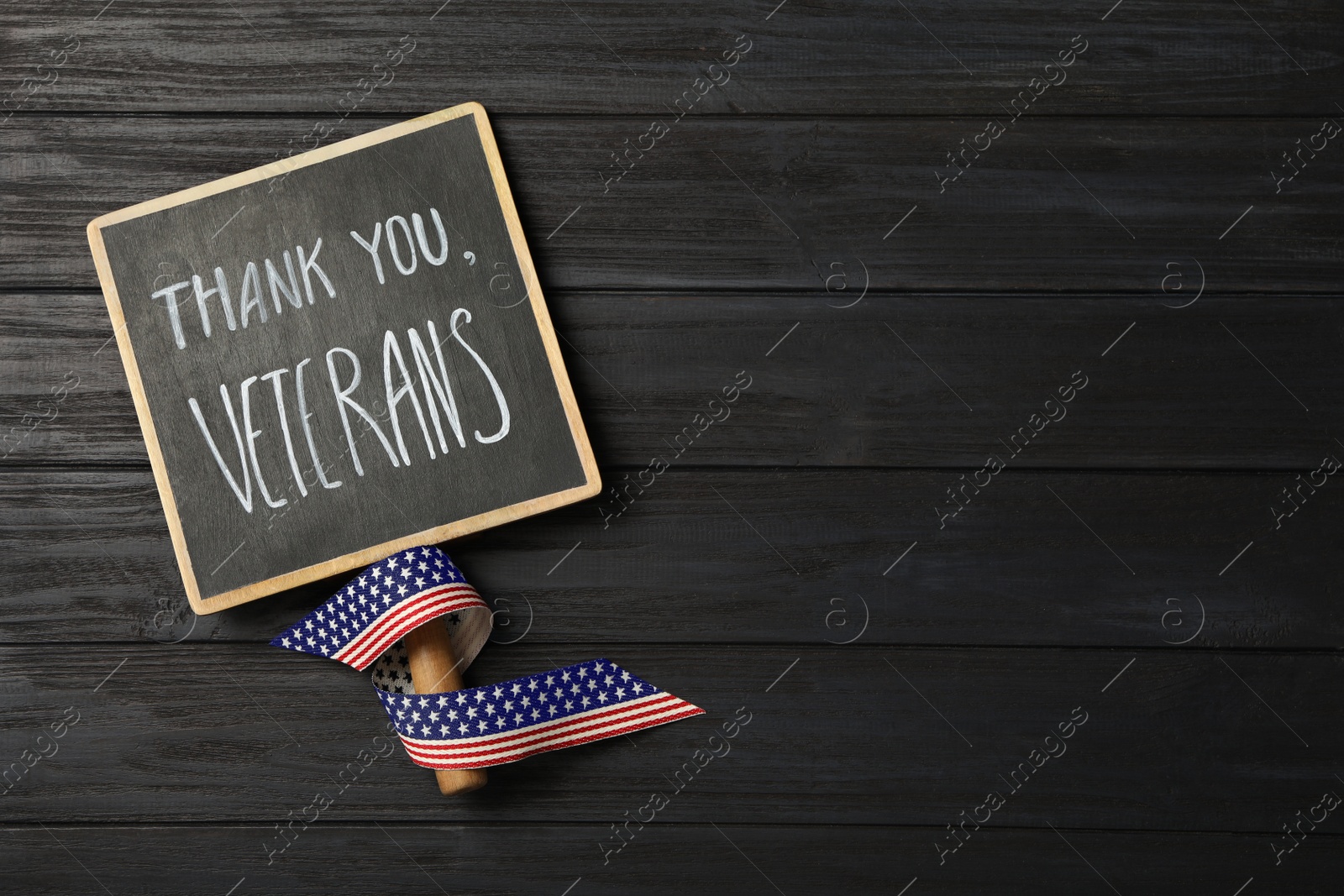 Photo of Sign with phrase Thank You, Veterans and ribbon on black wooden table, top view. Space for text