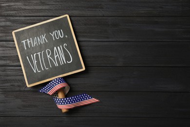 Photo of Sign with phrase Thank You, Veterans and ribbon on black wooden table, top view. Space for text