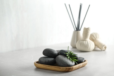 Photo of Spa stones and green leaf on light grey table. Space for text