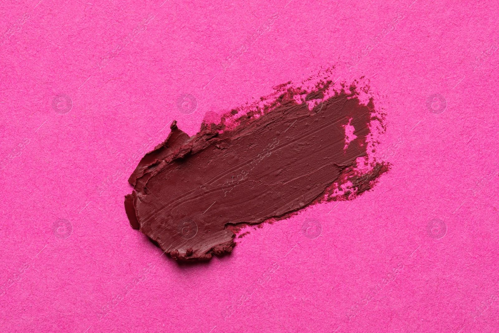 Photo of Smear of beautiful lipstick on pink background, top view