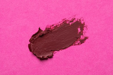 Photo of Smear of beautiful lipstick on pink background, top view
