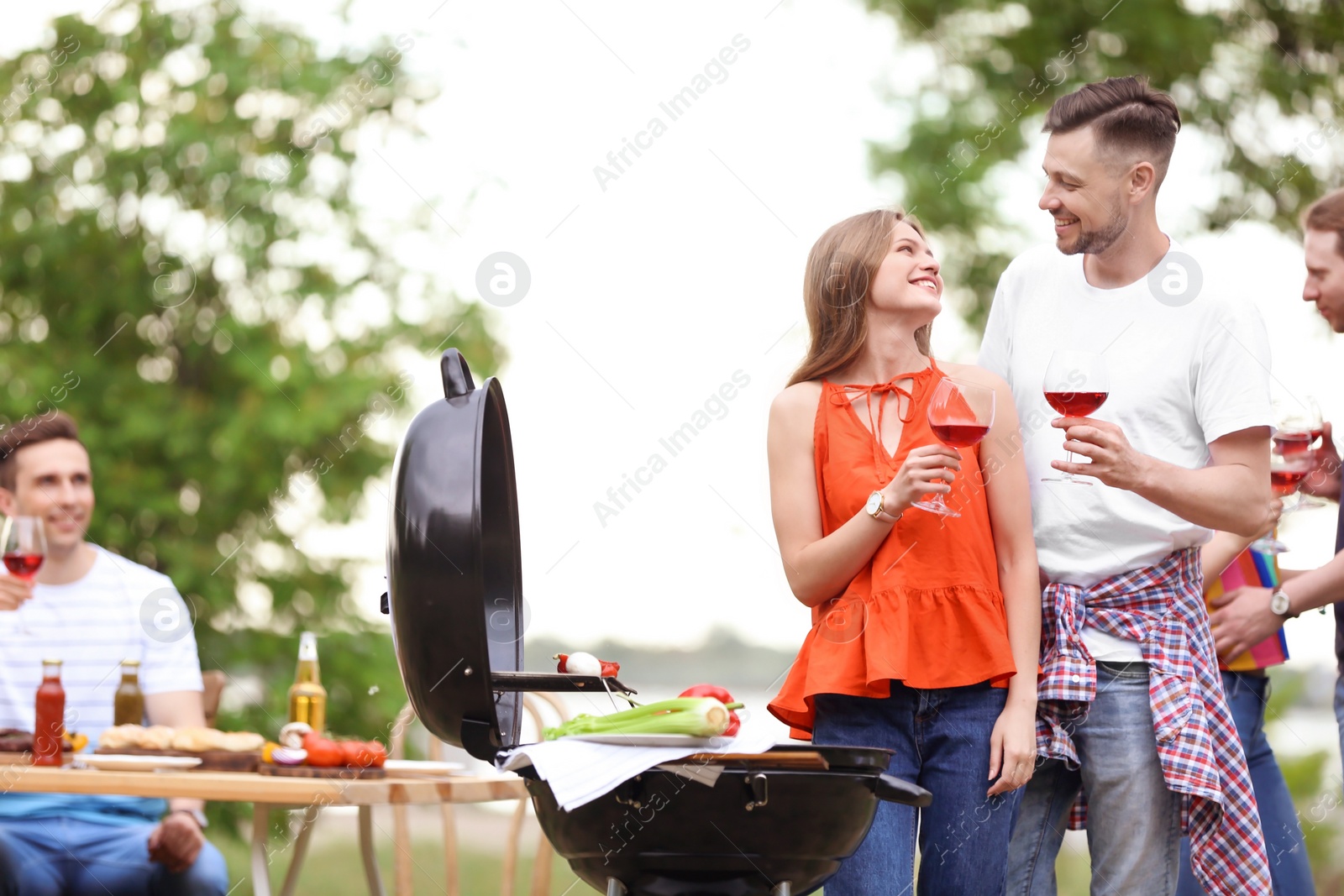 Photo of Young people having barbecue with modern grill outdoors