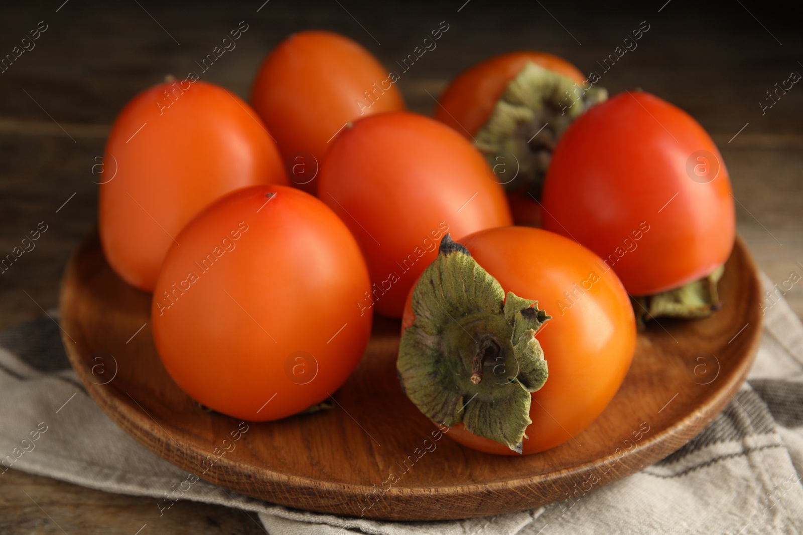 Photo of Tasty ripe persimmons on wooden table, closeup