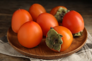 Photo of Tasty ripe persimmons on wooden table, closeup