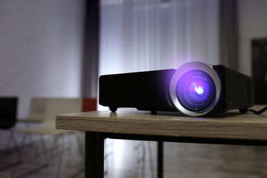 Photo of Modern video projector on wooden table in conference room