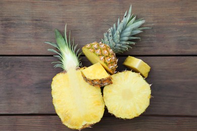 Cut ripe pineapples on wooden table, flat lay