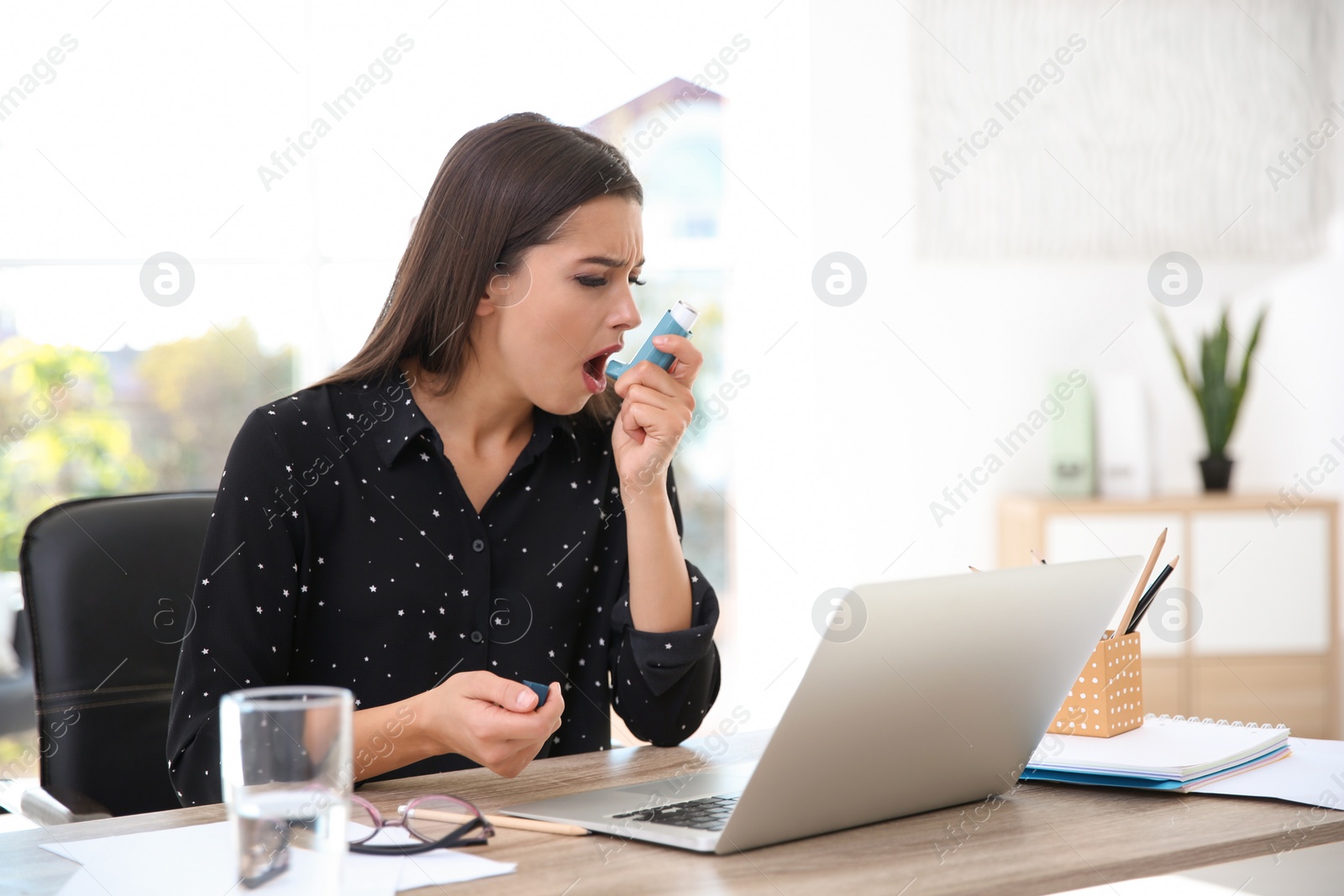 Photo of Woman with asthma inhaler at table in light room